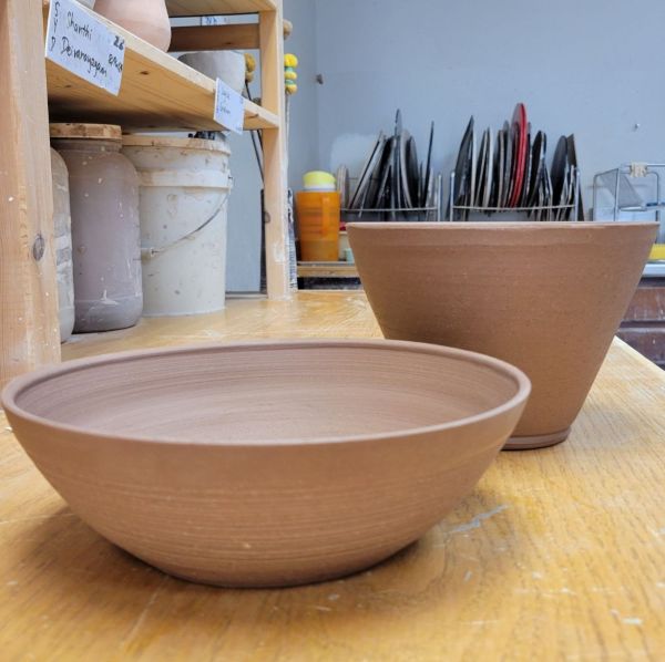 Two differently shaped greenware bowls made with red clay.