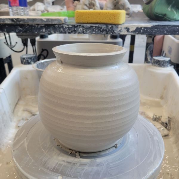 A large greenware pot thrown on the potter's wheel.