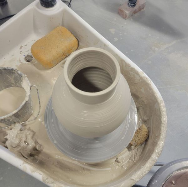 A large greenware pot thrown on the potter's wheel.