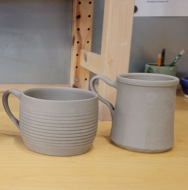 Two greenware mugs sitting side-by-side.